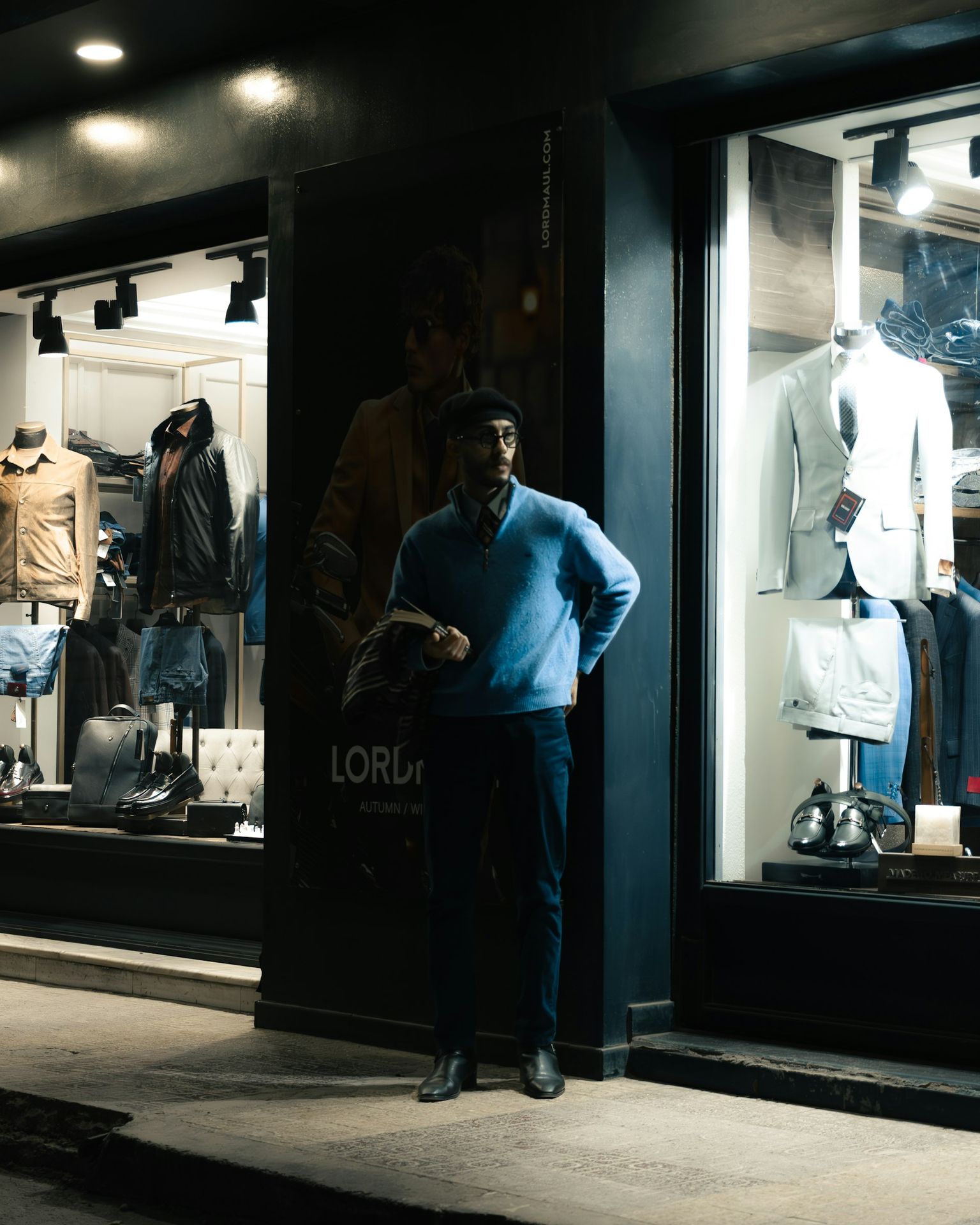 Man standing outside a clothing store at night.
